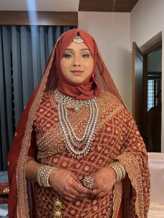 Bride in a rust embroidered outfit and hijab with layered pearl and gold jewellery — makeup by Popyz Beauty Lounge, Kozhikode