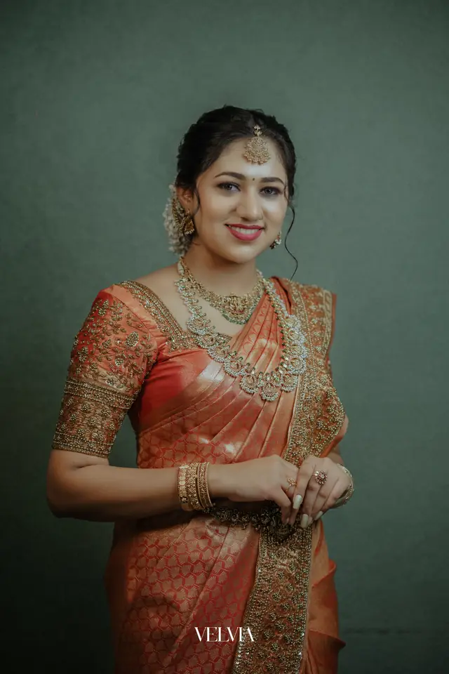 Kerala bride in an orange silk saree with gold jewellery