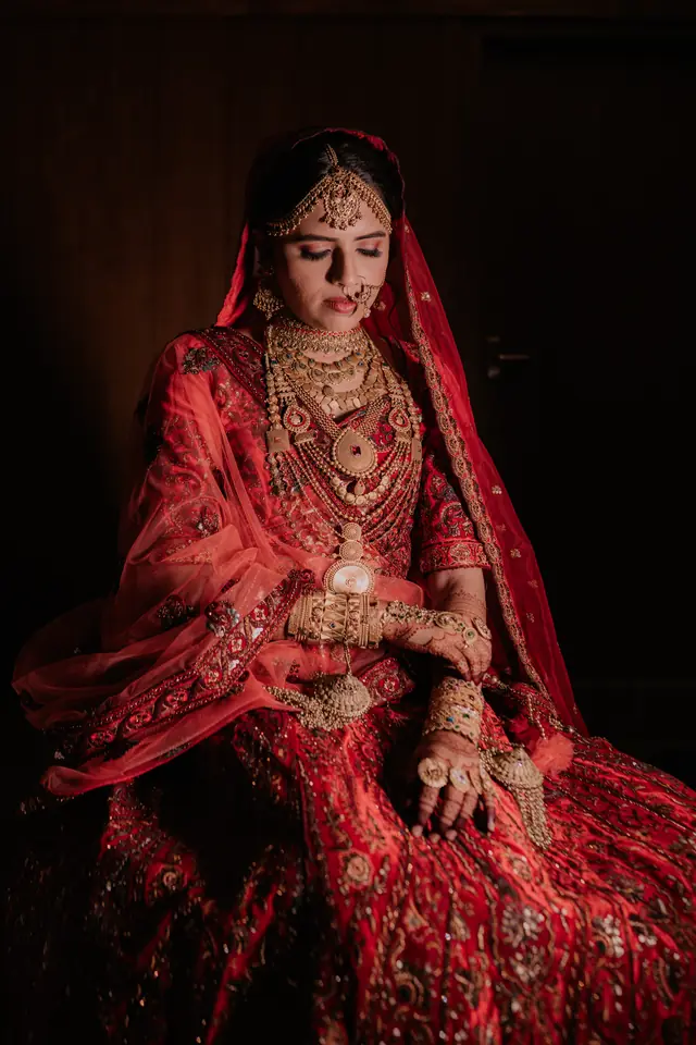 Bride in a red lehenga and dupatta with heavy gold and kundan jewellery — makeup by Popyz Beauty Lounge, Kozhikode