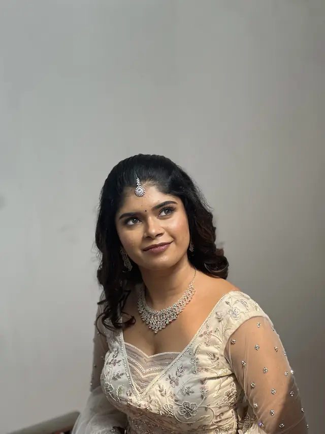 Bride in an ivory lehenga with a delicate diamond necklace and soft makeup — makeup by Popyz Beauty Lounge, Kozhikode