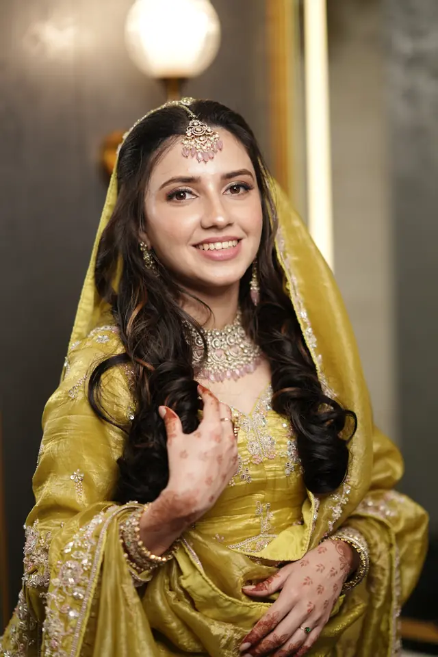 Bride in a mustard lehenga and sheer dupatta with a gold matha patti