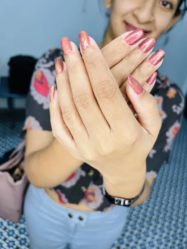 Close-up of two hands with glossy pink almond-shaped nails